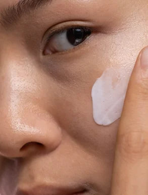 Application précise d'un soin hydratant sur le visage, révélant la texture délicate et l'efficacité des produits Derma'Love pour une peau éclatante et bien nourrie.