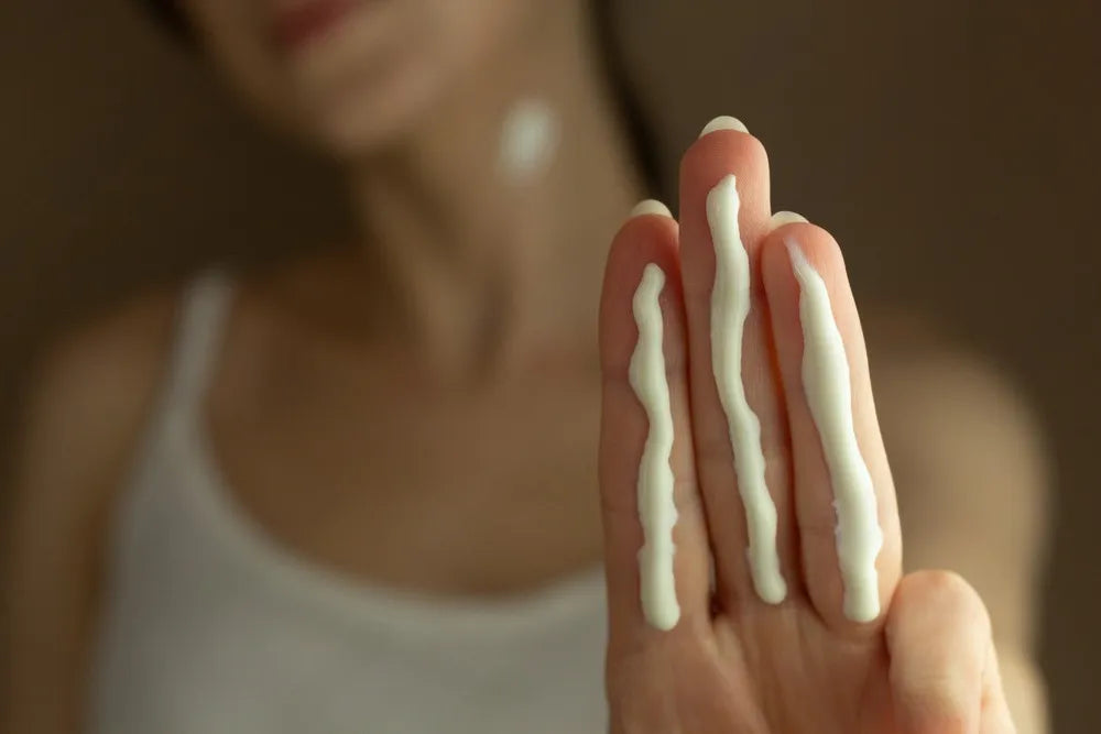 Main appliquant une crème hydratante avec des lignes fluides, symbolisant la précision et la texture délicate des soins Derma'Love pour une peau douce et bien nourrie.