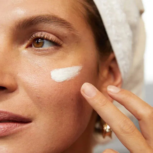 Gros plan sur une femme appliquant délicatement une crème Derma'Love sur sa joue. Sa peau naturelle et lumineuse met en valeur l'efficacité de nos soins. L'image illustre la routine beauté quotidienne pour une peau saine et éclatante, grâce aux produits Derma'Love.