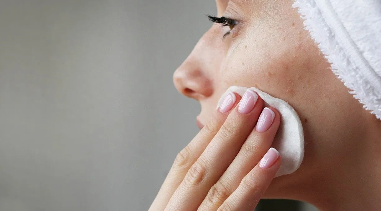 Gros plan sur une femme appliquant délicatement un soin Derma'Love sur sa joue. Sa peau semble douce et hydratée, illustrant l'efficacité des produits. Le geste précis et le regard concentré mettent en valeur l'importance d'une routine de soins quotidienne pour une peau éclatante de santé.