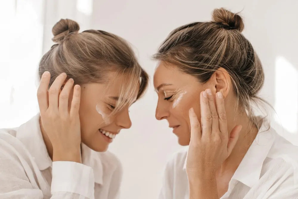 Duo génrationnel illustrant l'efficacité des soins anti-âge Derma'Love, femme mature et jeune femme appliquant une crème hydratante, symbolisant la transmission et l'expertise en soin de la peau.