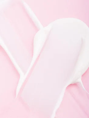 Texture délicate de soin hydratant sur fond rose, illustrant la douceur et la précision des produits Derma'Love pour une peau éclatante et naturellement belle.