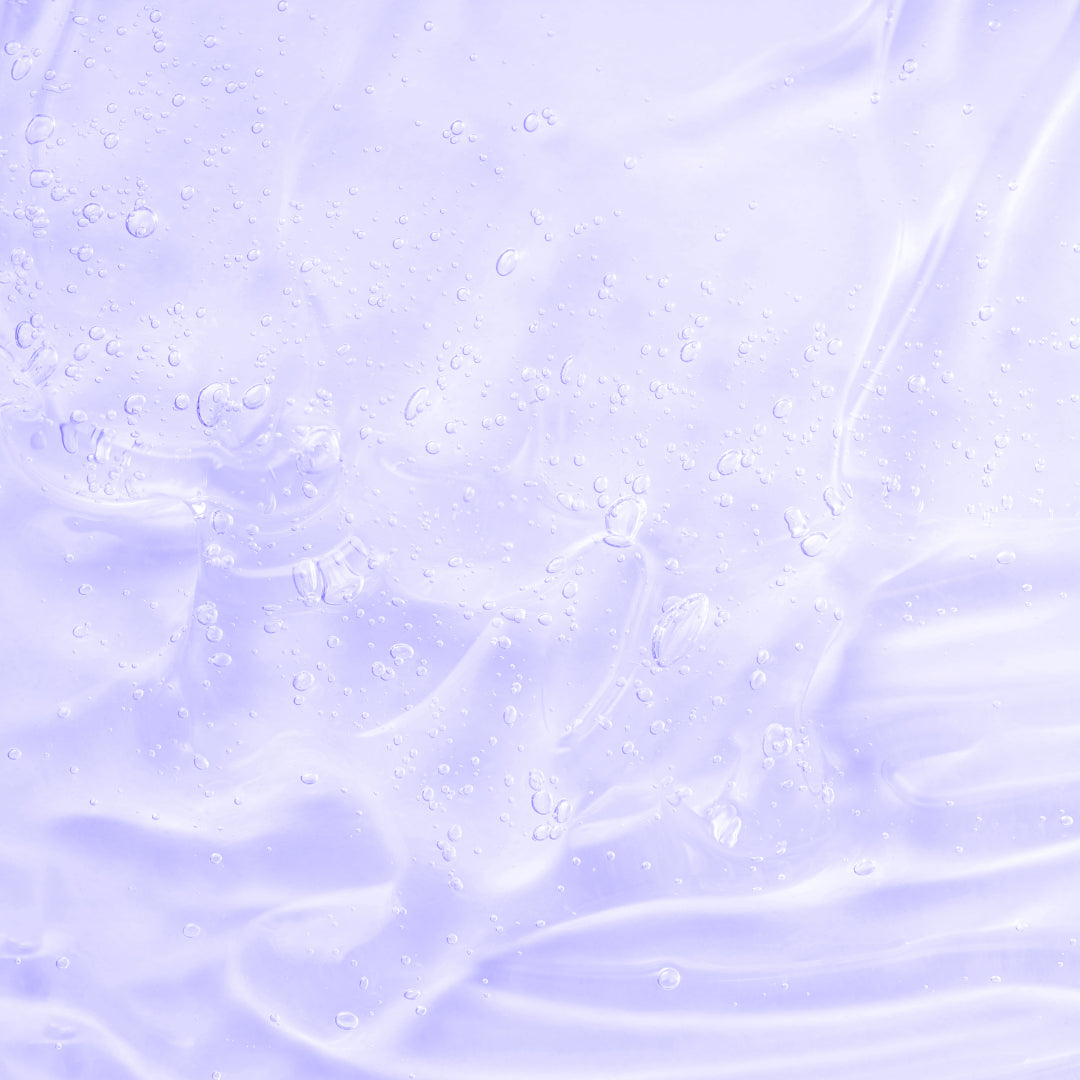 Texture soyeuse et hydratante des soins Derma'Love : gouttelettes cristallines sur fond lilas délicat, illustrant la légèreté et l'efficacité de nos formules bio certifiées. La transparence et la pureté de nos actifs naturels capturées en macro.